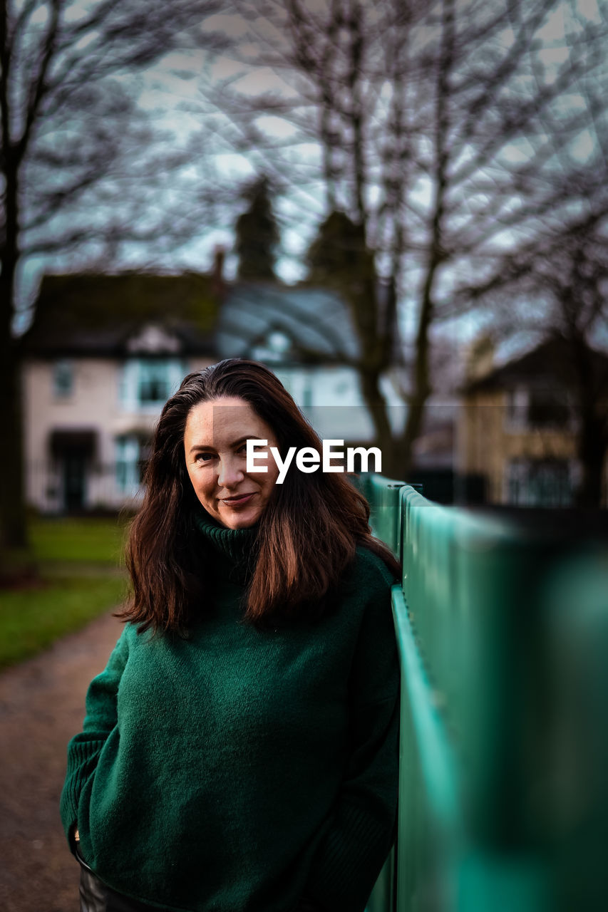 Portrait of smiling woman standing against trees