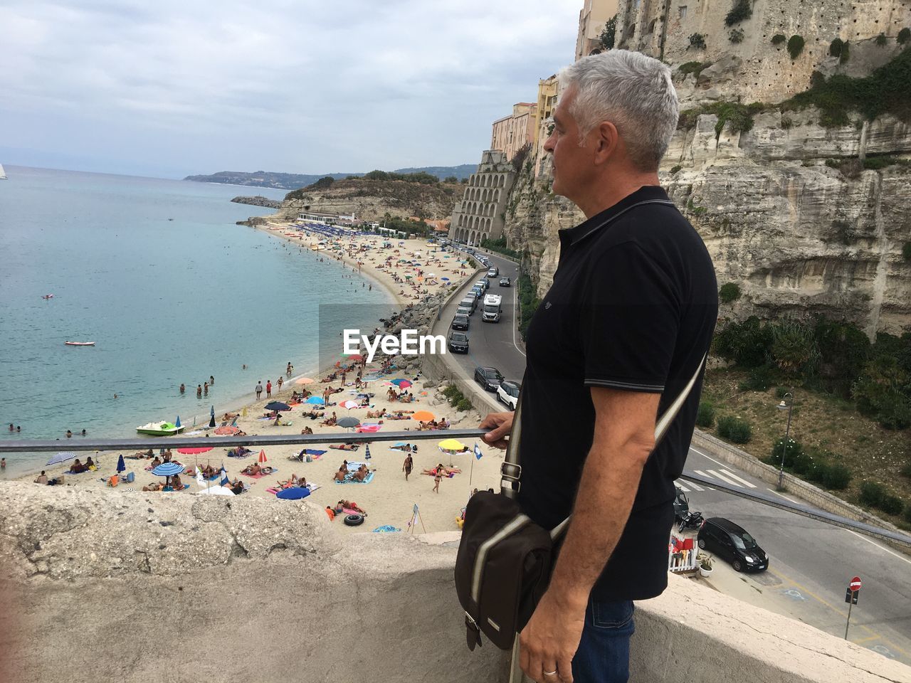 Mature man looking away while standing against sea