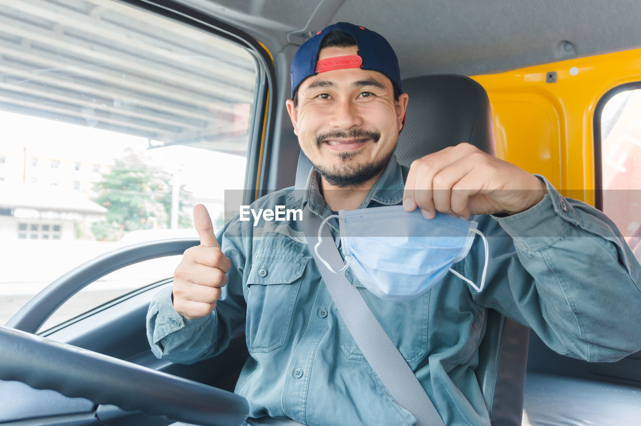 Portrait of driver showing mask in vehicle