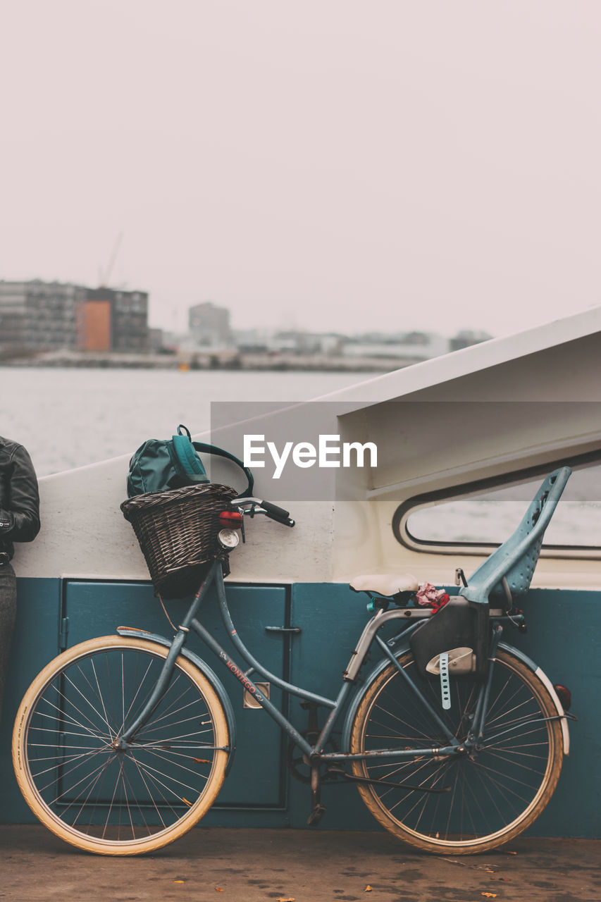 Bicycle parked by sea against sky