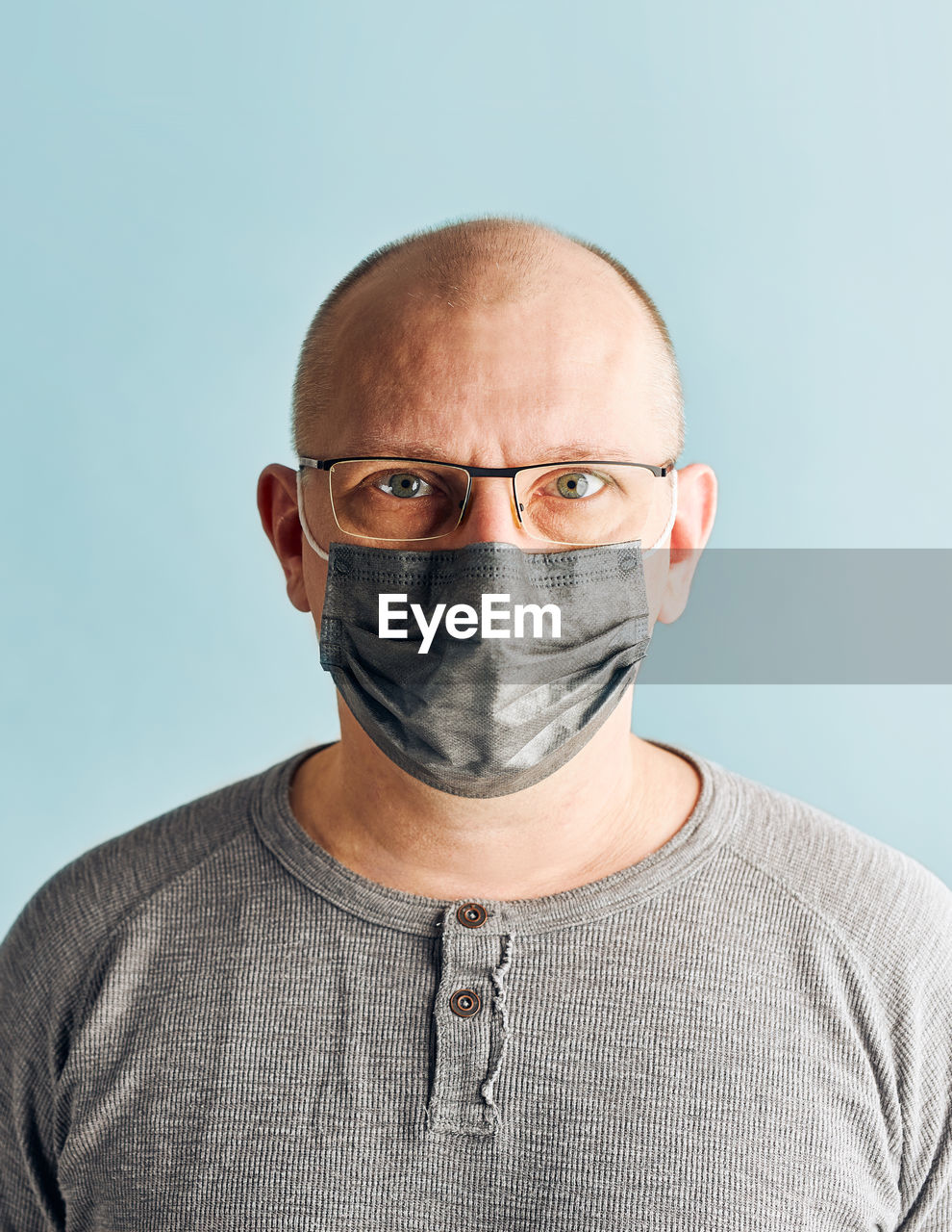 CLOSE-UP PORTRAIT OF MAN WEARING EYEGLASSES AGAINST GRAY BACKGROUND