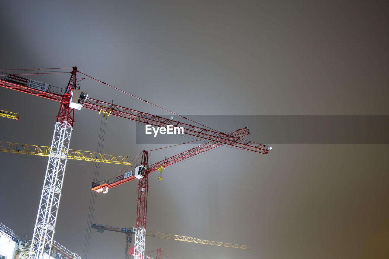 Low angle view of cranes against sky at night