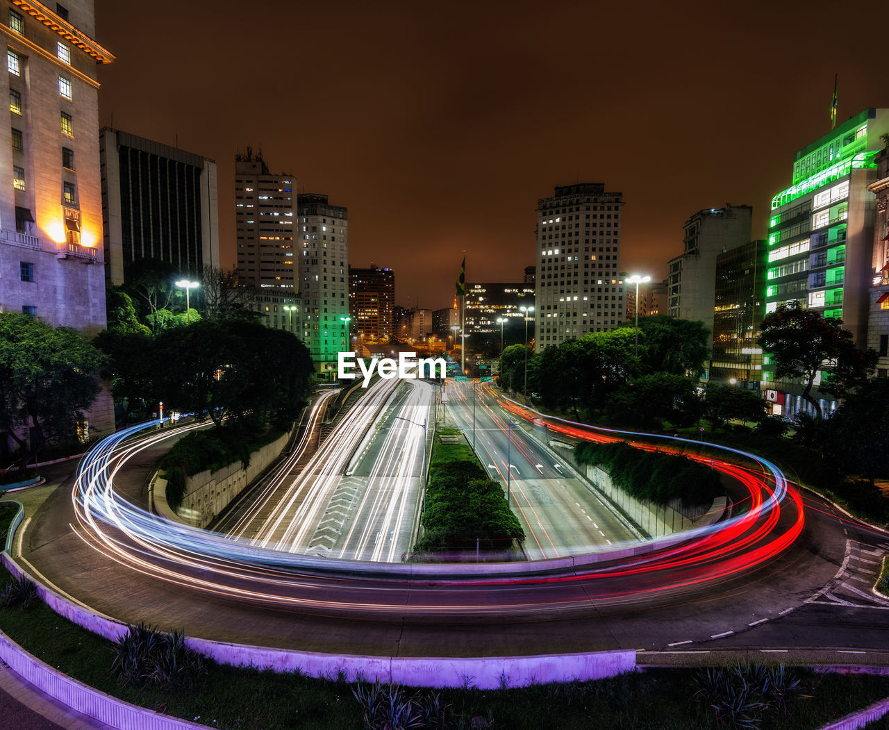 Light trails on street amidst buildings in city at night