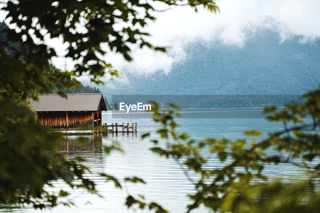 Scenic view of lake against sky with small cottage 