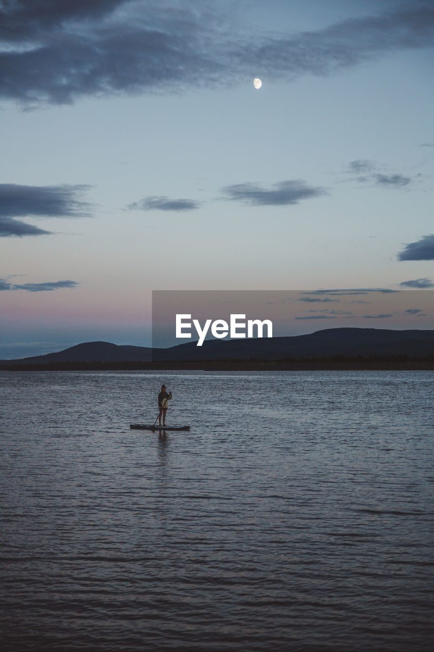 Woman on stand up paddle board at sea at night