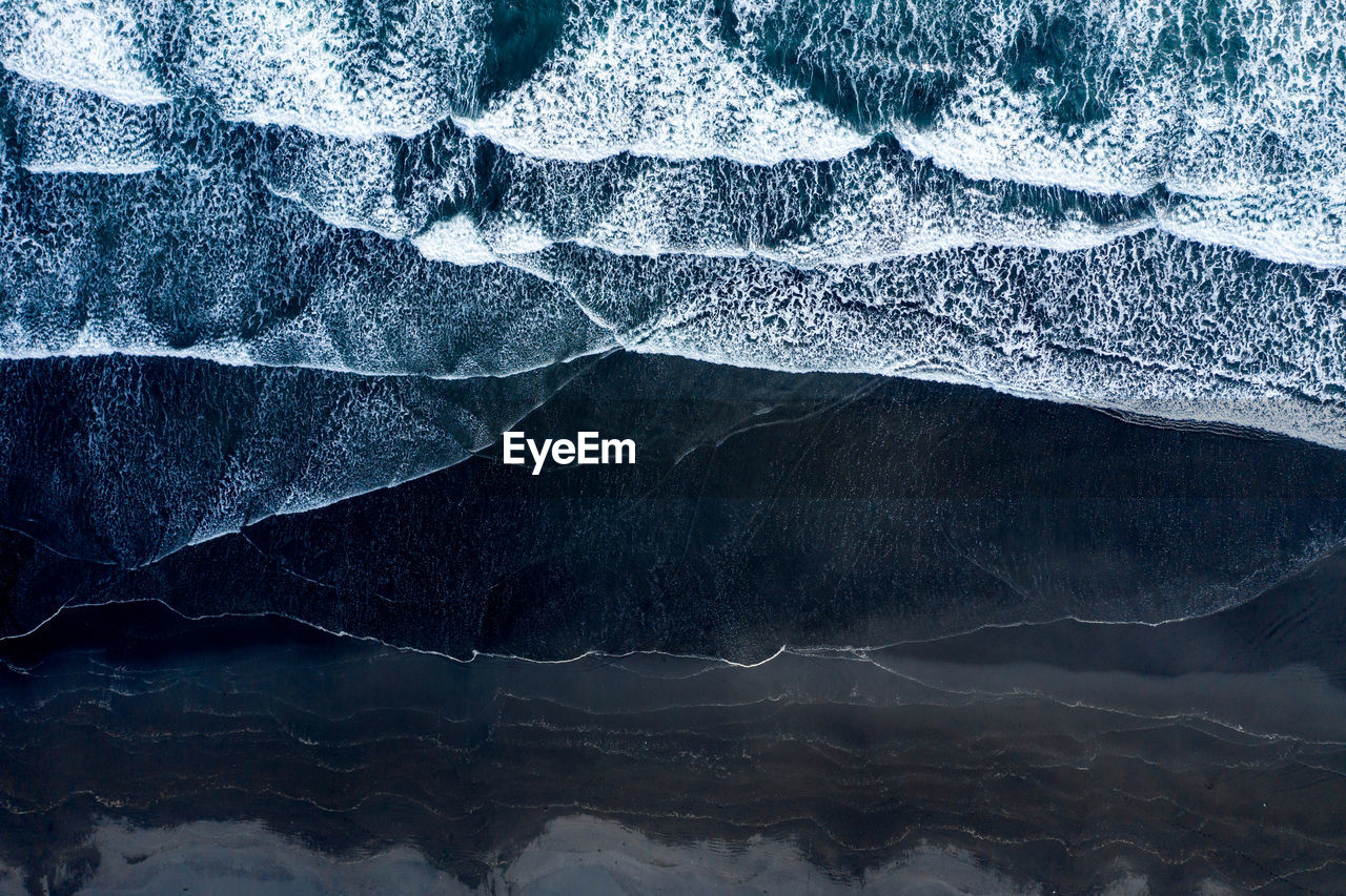 Aerial view of sea waves washing black sandy beach. hofn, iceland