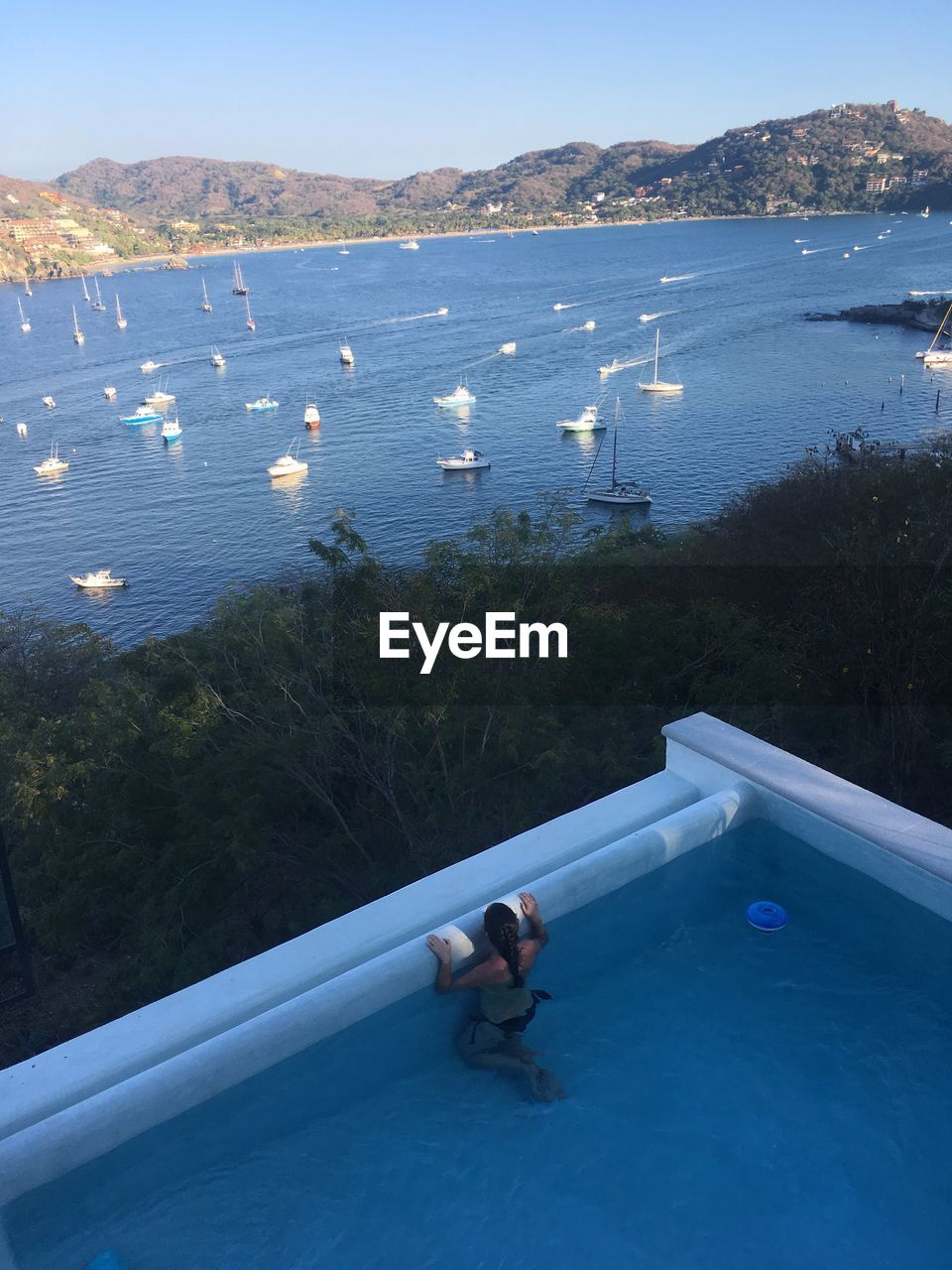 High angle view of woman in infinity pool against lake