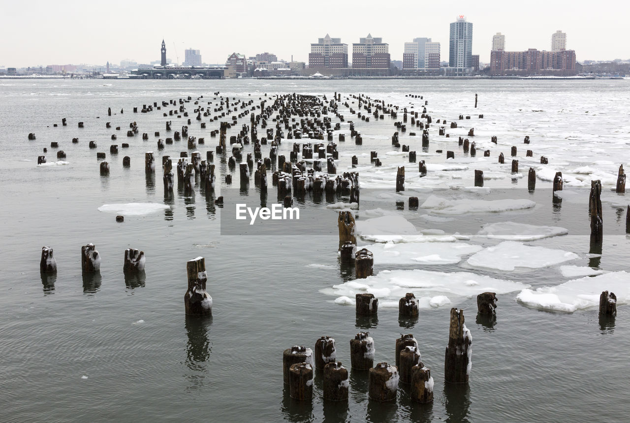 High angle view of wooden posts in river during winter