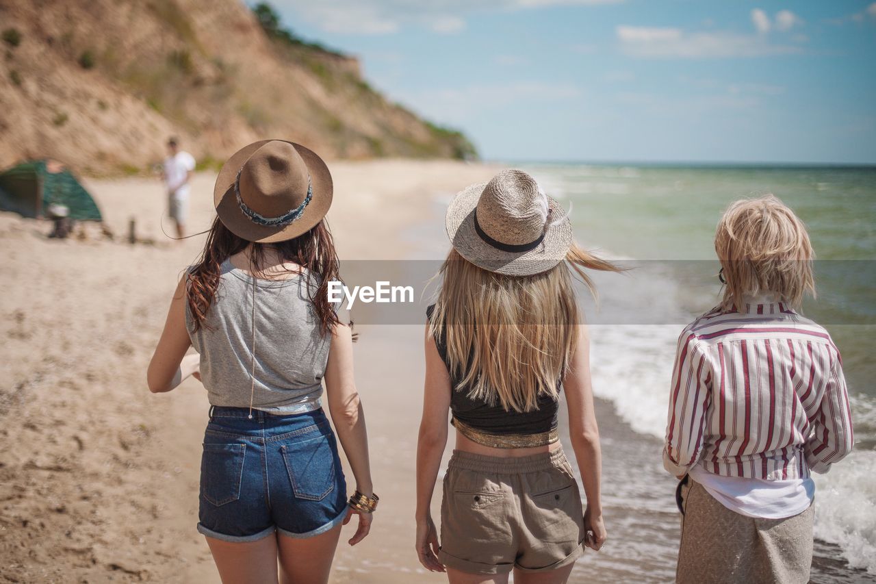 Rear view of friends standing on beach