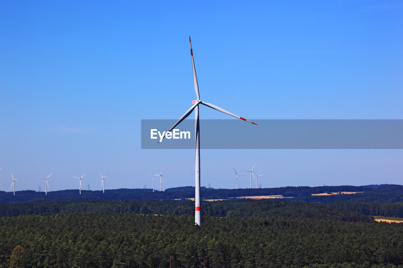 WINDMILLS ON FIELD AGAINST SKY