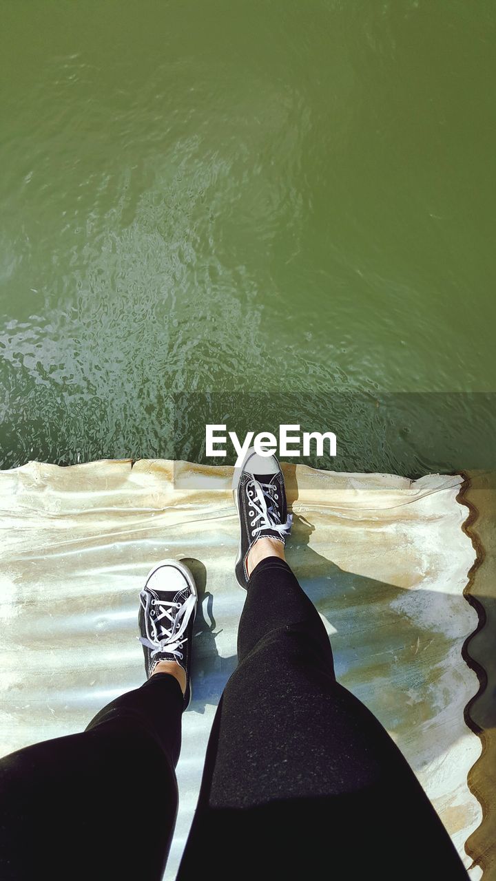 Low section of woman standing over lake