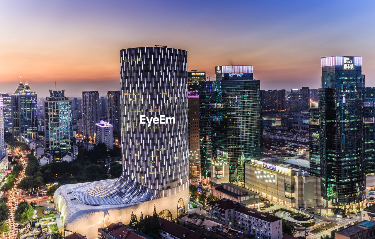 Illuminated modern buildings against sky during sunset