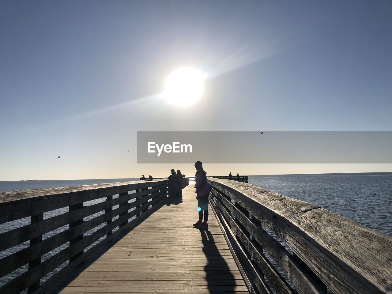 SILHOUETTE MAN STANDING ON PIER OVER SEA AGAINST CLEAR SKY