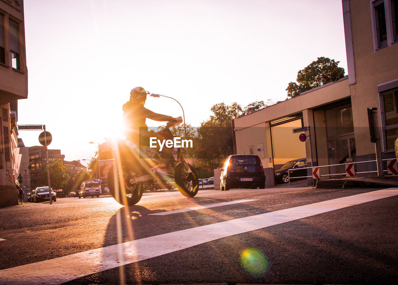 MAN RIDING BICYCLE ON ROAD AGAINST SKY