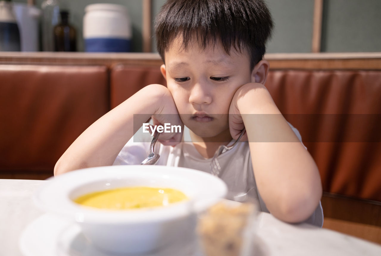 Portrait of cute boy with ice cream in bowl on table