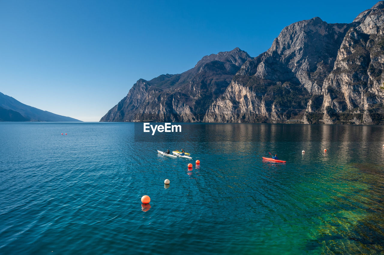 SCENIC VIEW OF SEA BY MOUNTAIN AGAINST CLEAR BLUE SKY