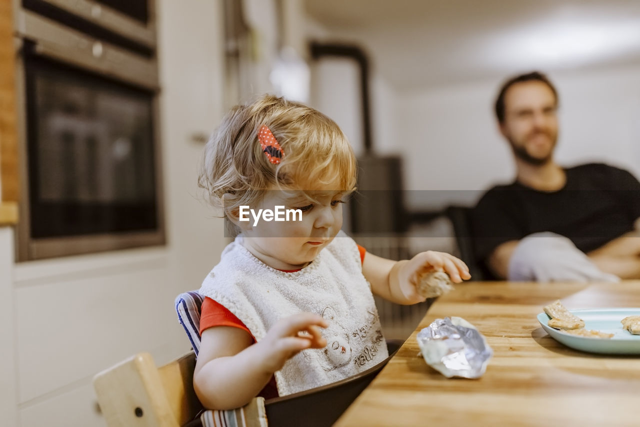 Baby girl sitting on high chair at home