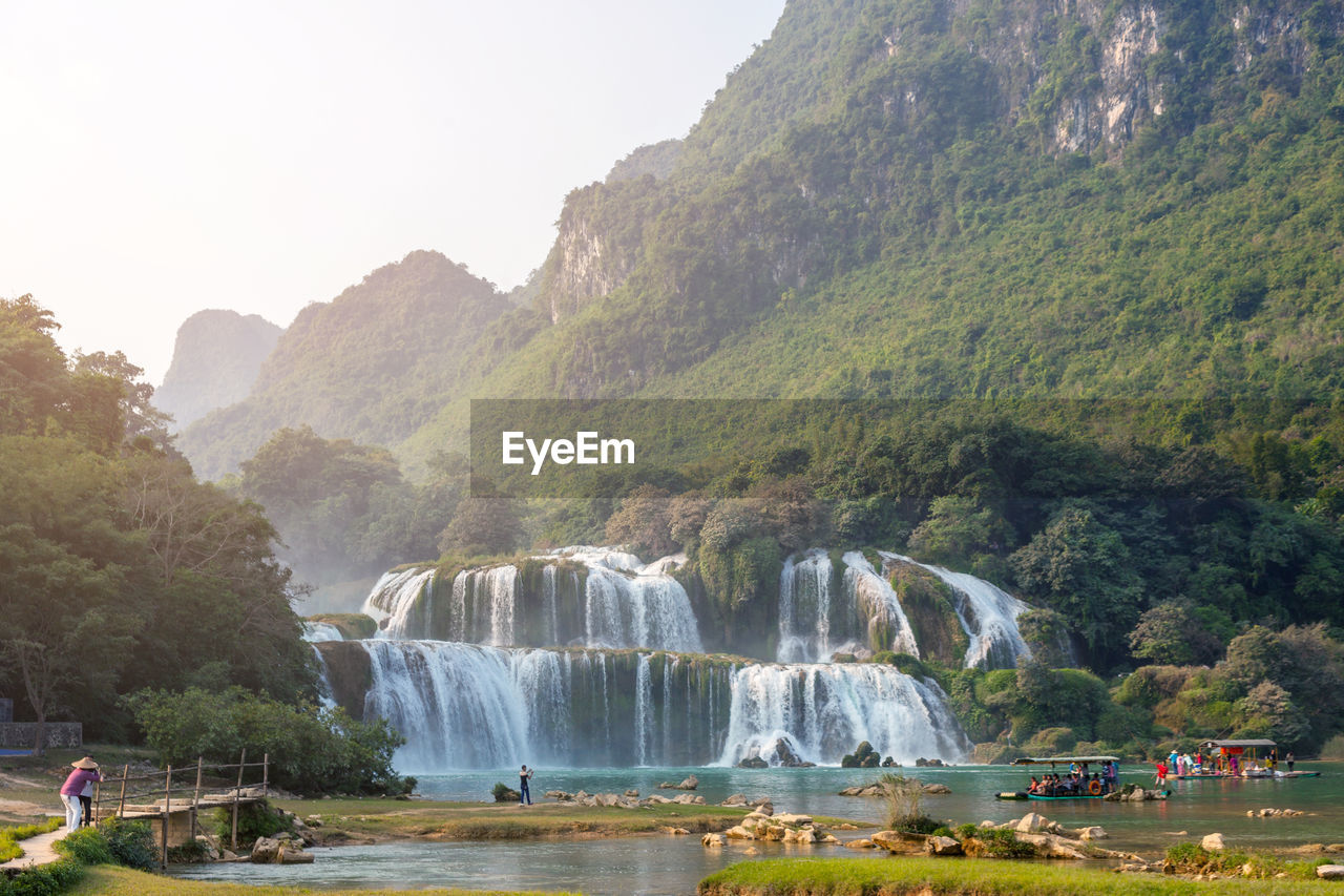 SCENIC VIEW OF WATERFALL AGAINST MOUNTAINS