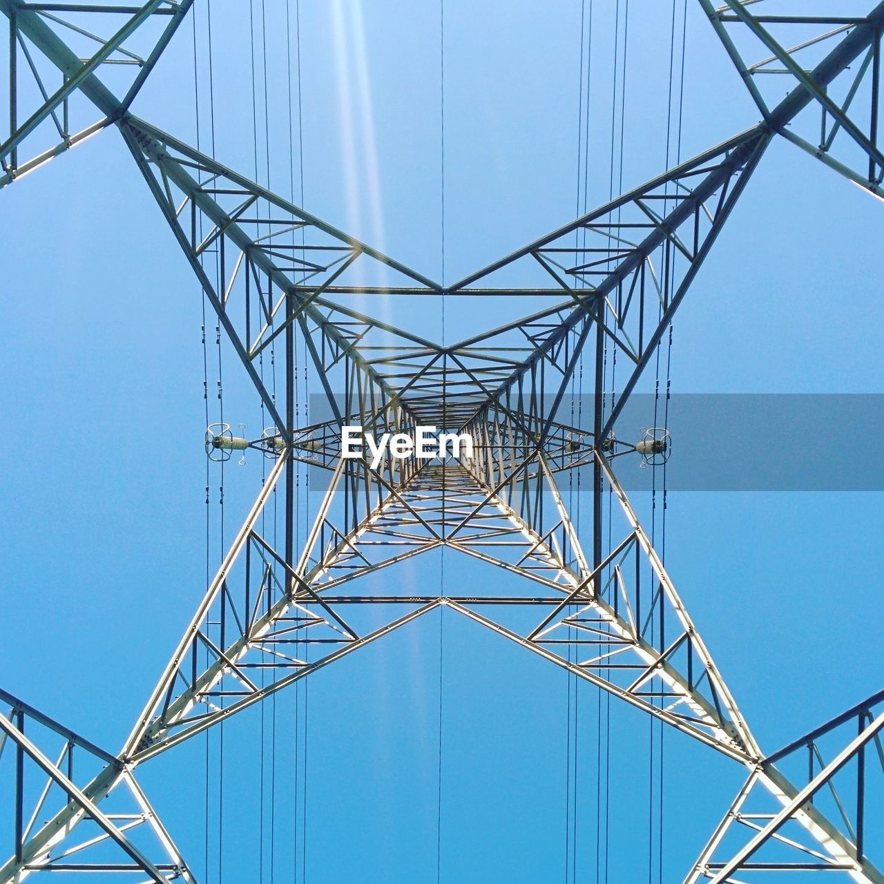 Low angle view of electricity pylon against clear blue sky