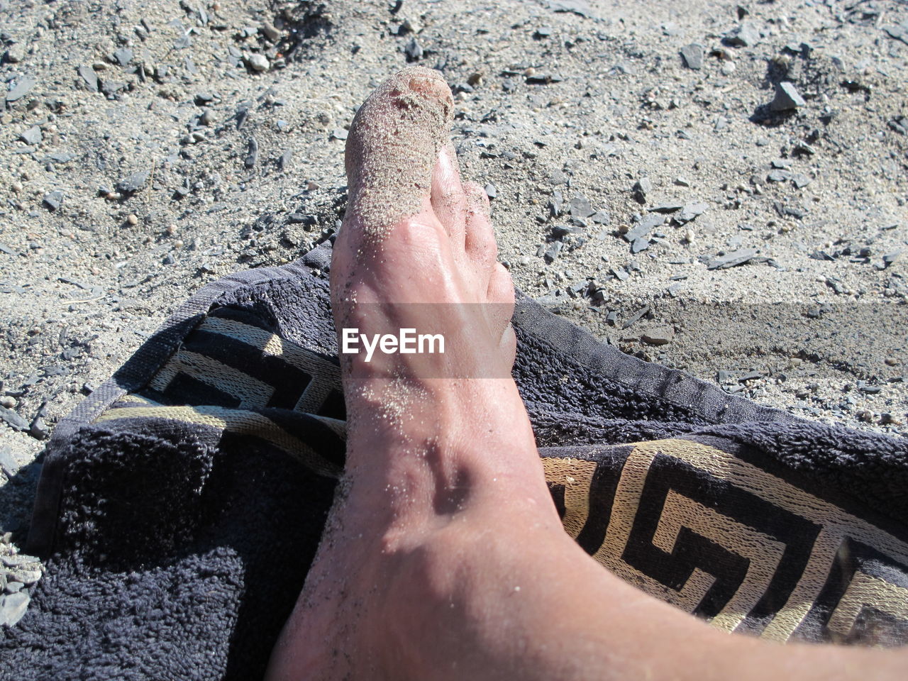 LOW SECTION OF PERSON FEET ON SAND AT BEACH