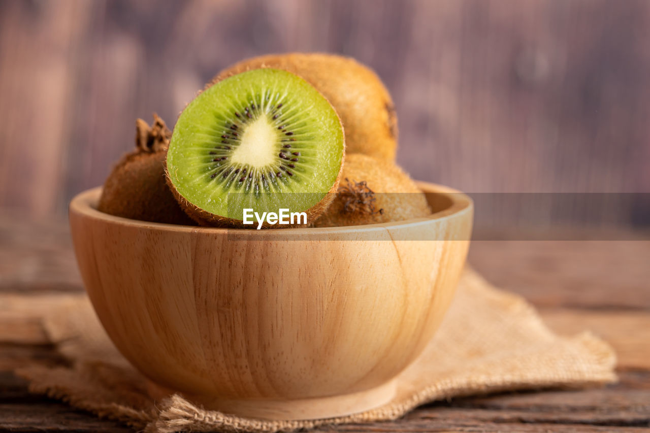 Close up a half of fresh green kiwi in a wood bowl with blurred background