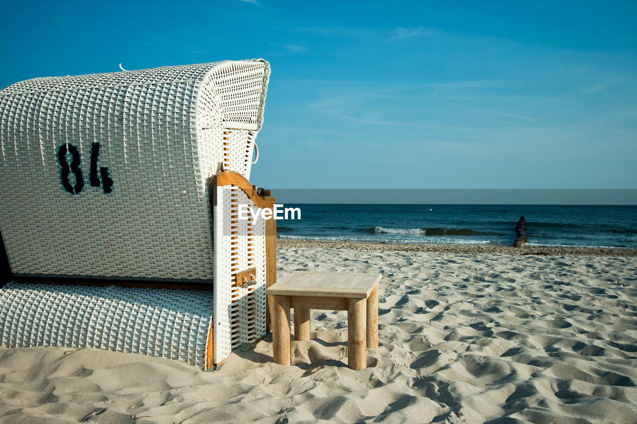 HOODED BEACH CHAIRS ON SAND AGAINST SEA