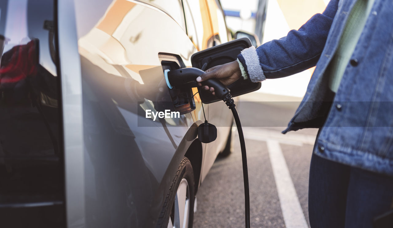 Young woman charging electric car at station