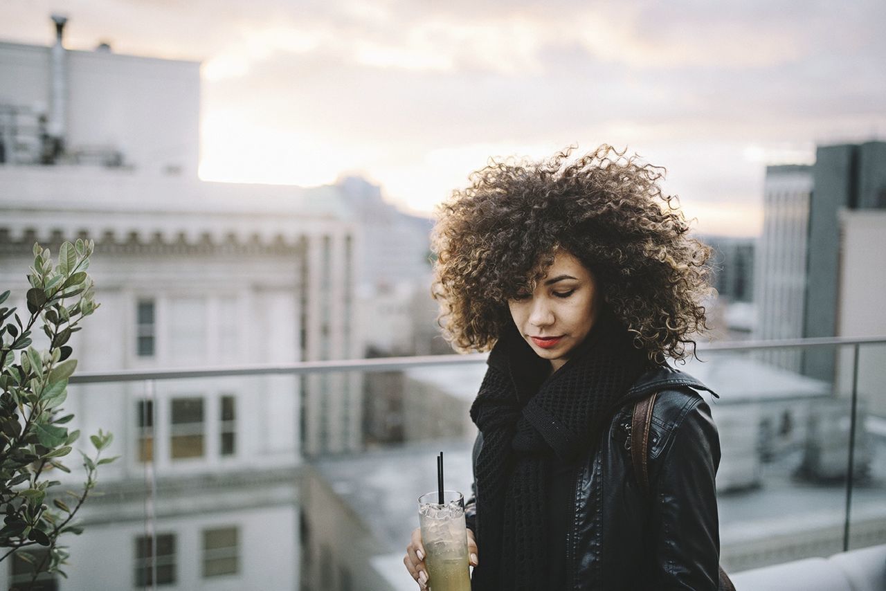 Portrait of beautiful woman standing against buildings in city