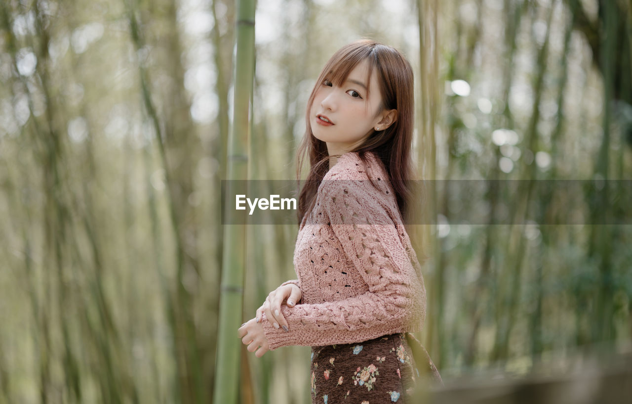 portrait of young woman standing in forest