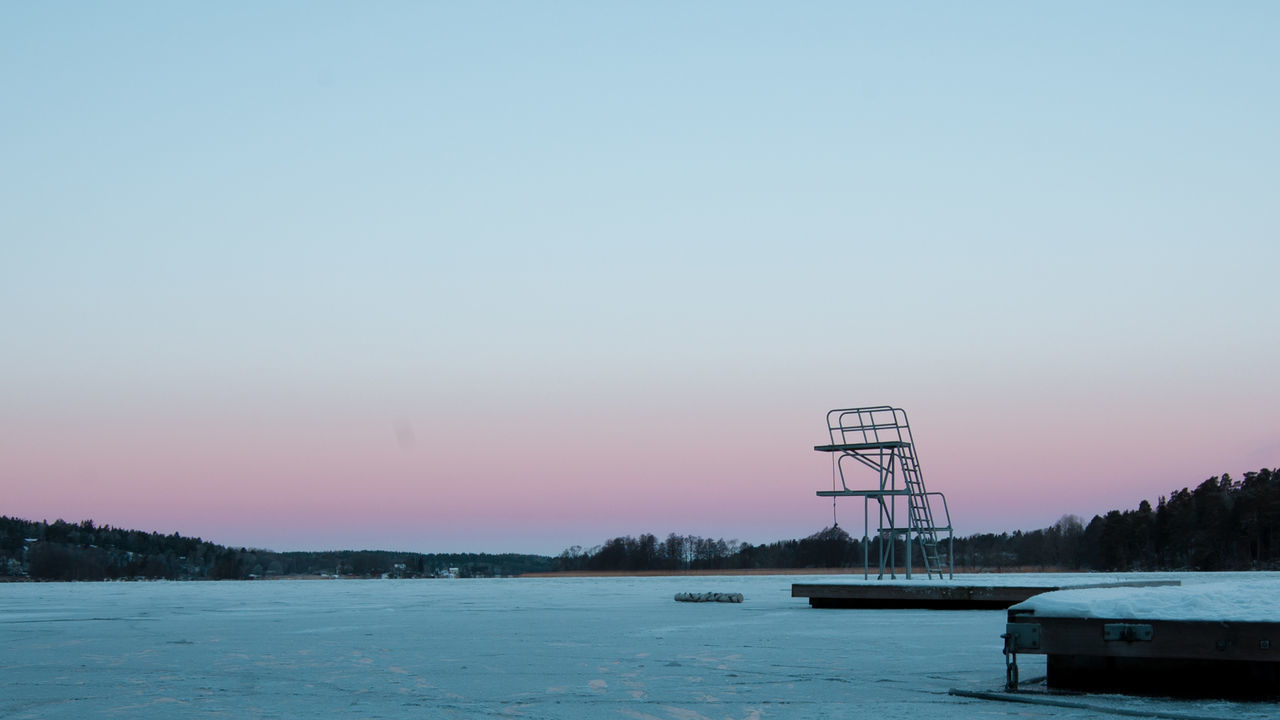 Diving board by river against clear sky at dusk