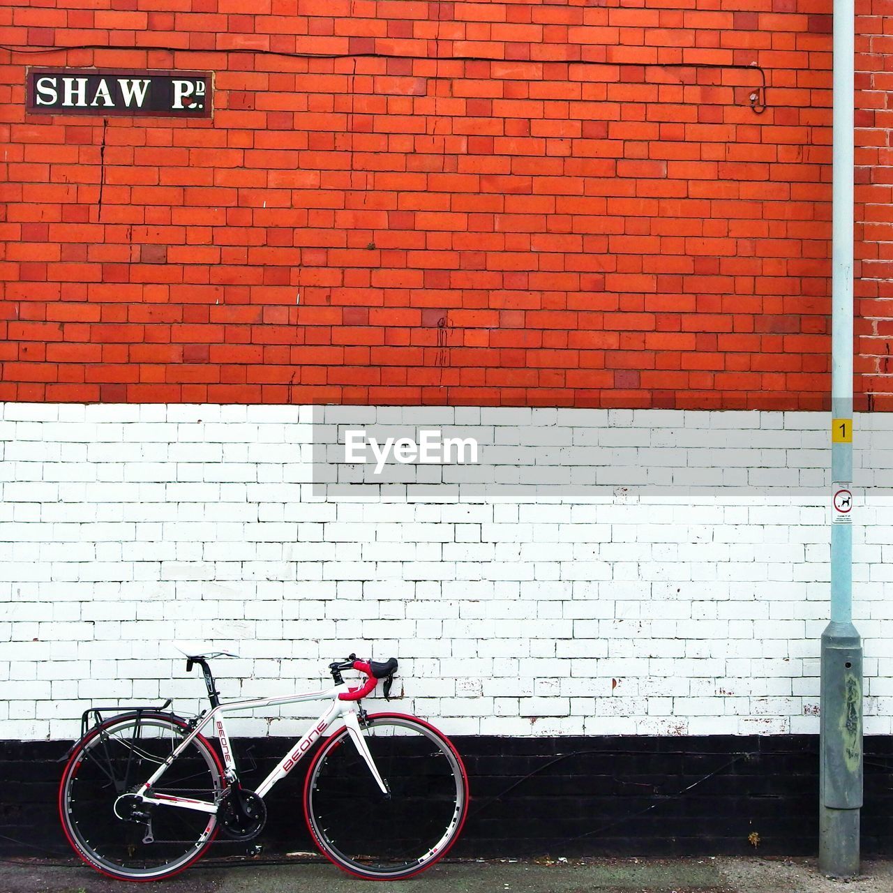 Bicycle parked on sidewalk against brick wall