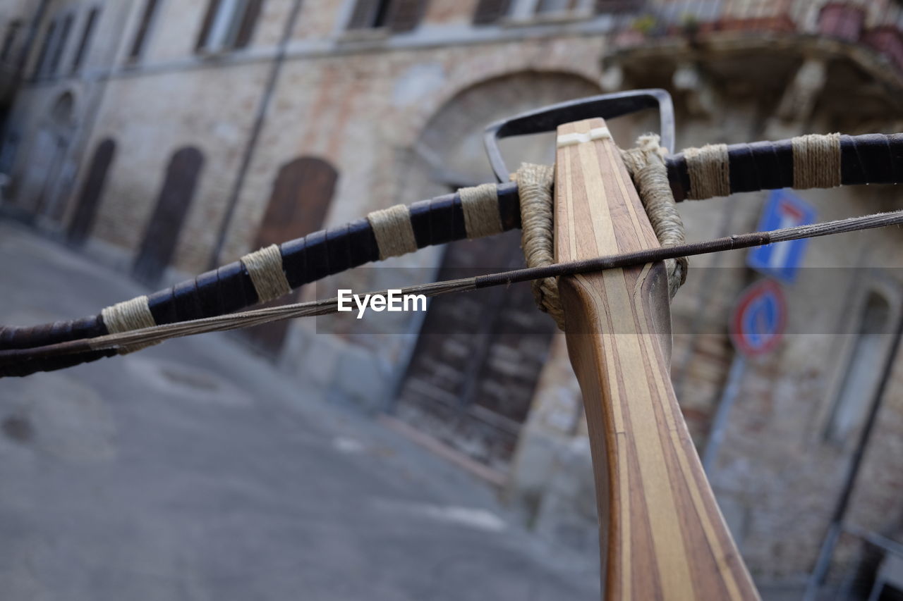 Close-up of wooden crossbow against buildings