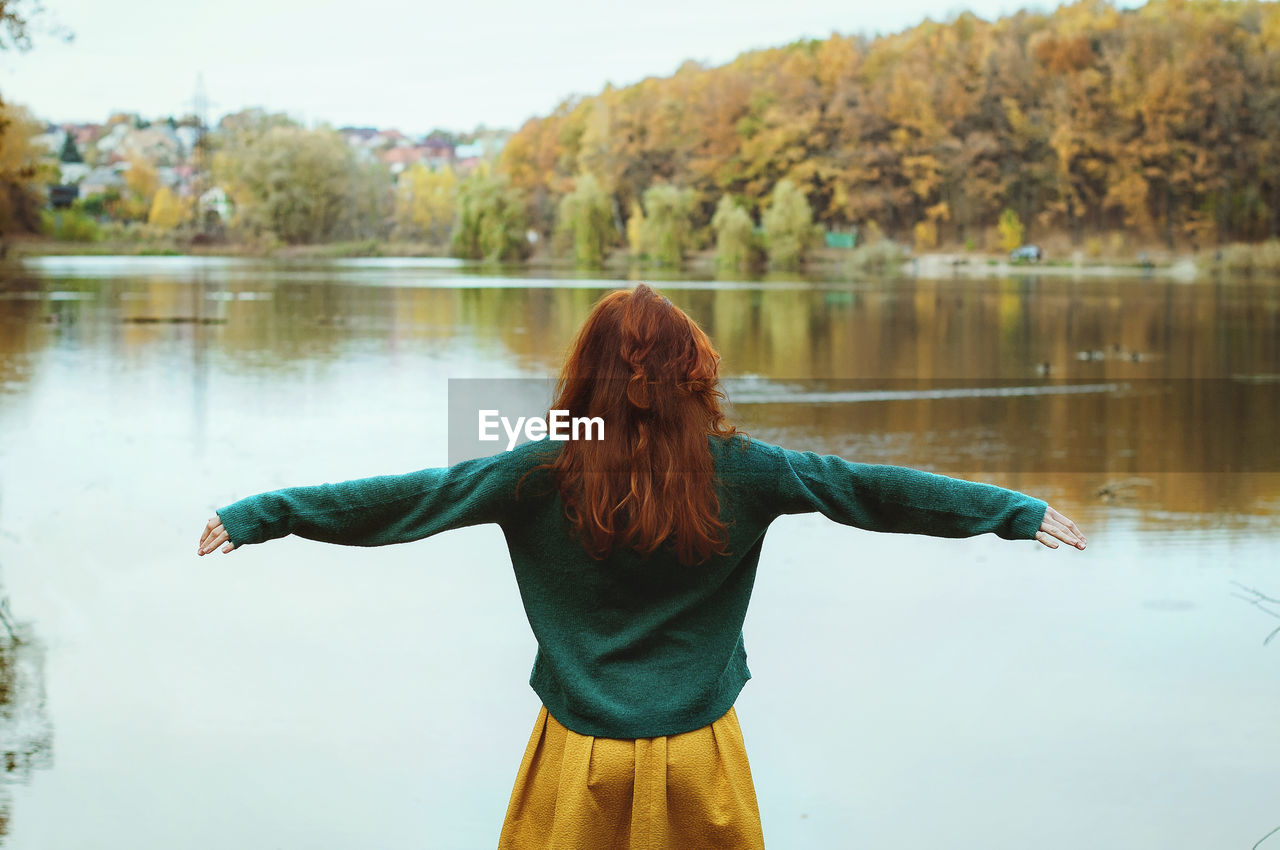 Autumn rear view of redhead woman standing in lake