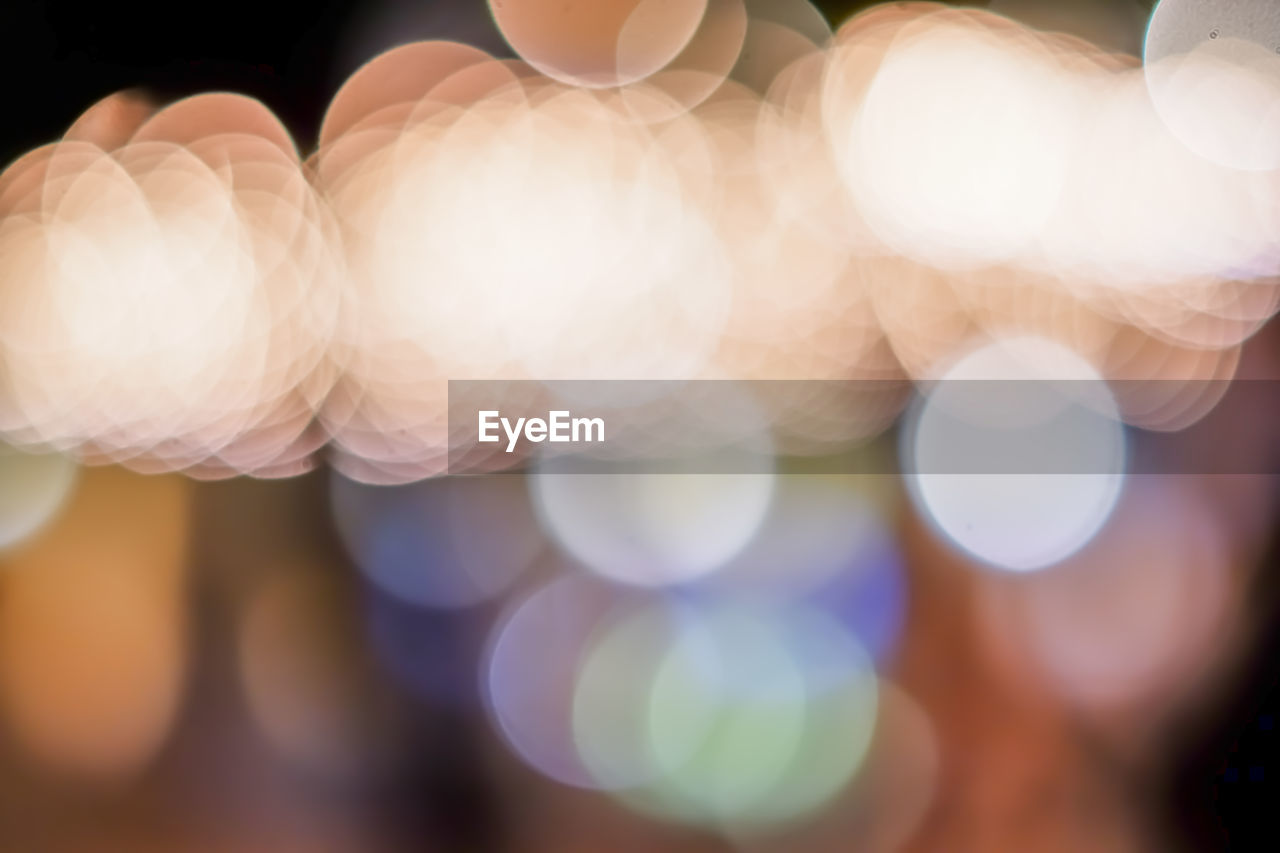 CLOSE-UP OF HAND HOLDING ILLUMINATED DEFOCUSED LIGHTS