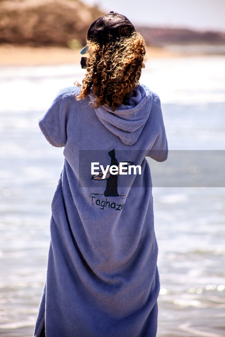 REAR VIEW OF WOMAN AT BEACH DURING SUNSET