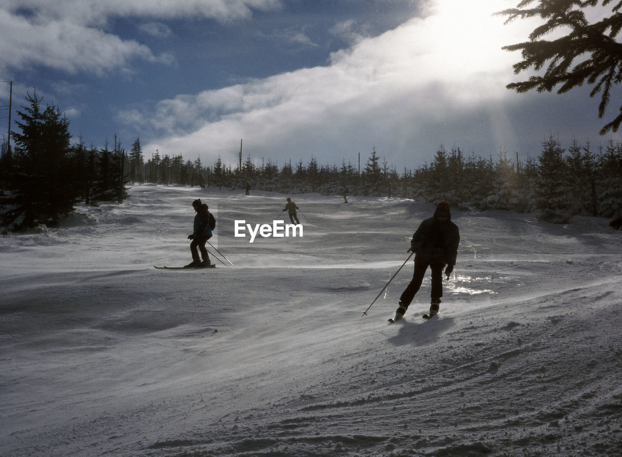 People on snow covered landscape against sky