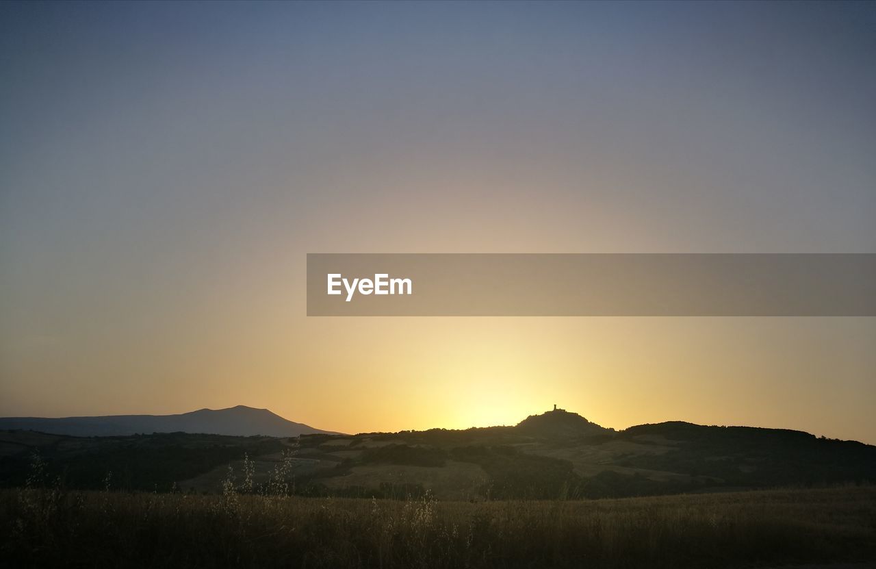 Scenic view of field against clear sky during sunset