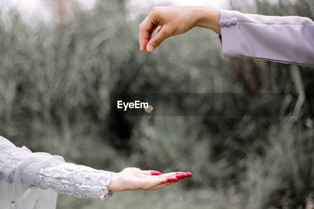 Cropped image of man throwing wedding ring on bride hand