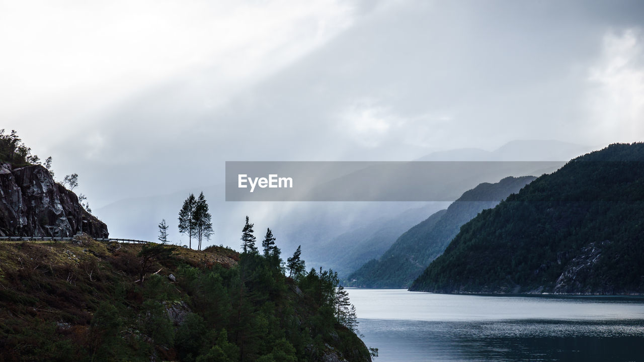 Scenic view of mountains and river against cloudy sky