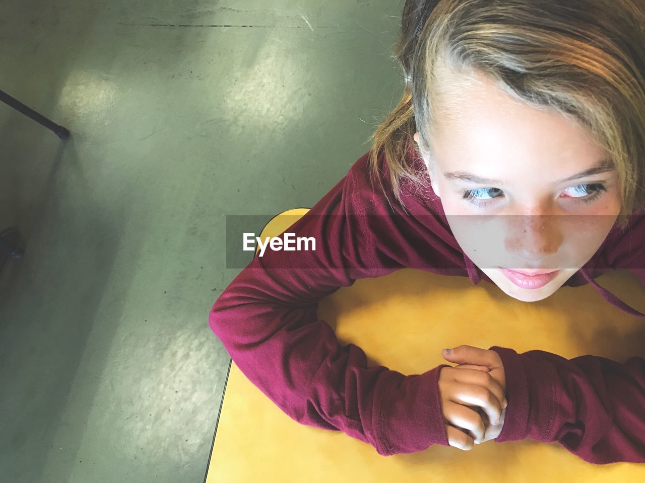 High angle view of girl looking away while sitting at table in restaurant