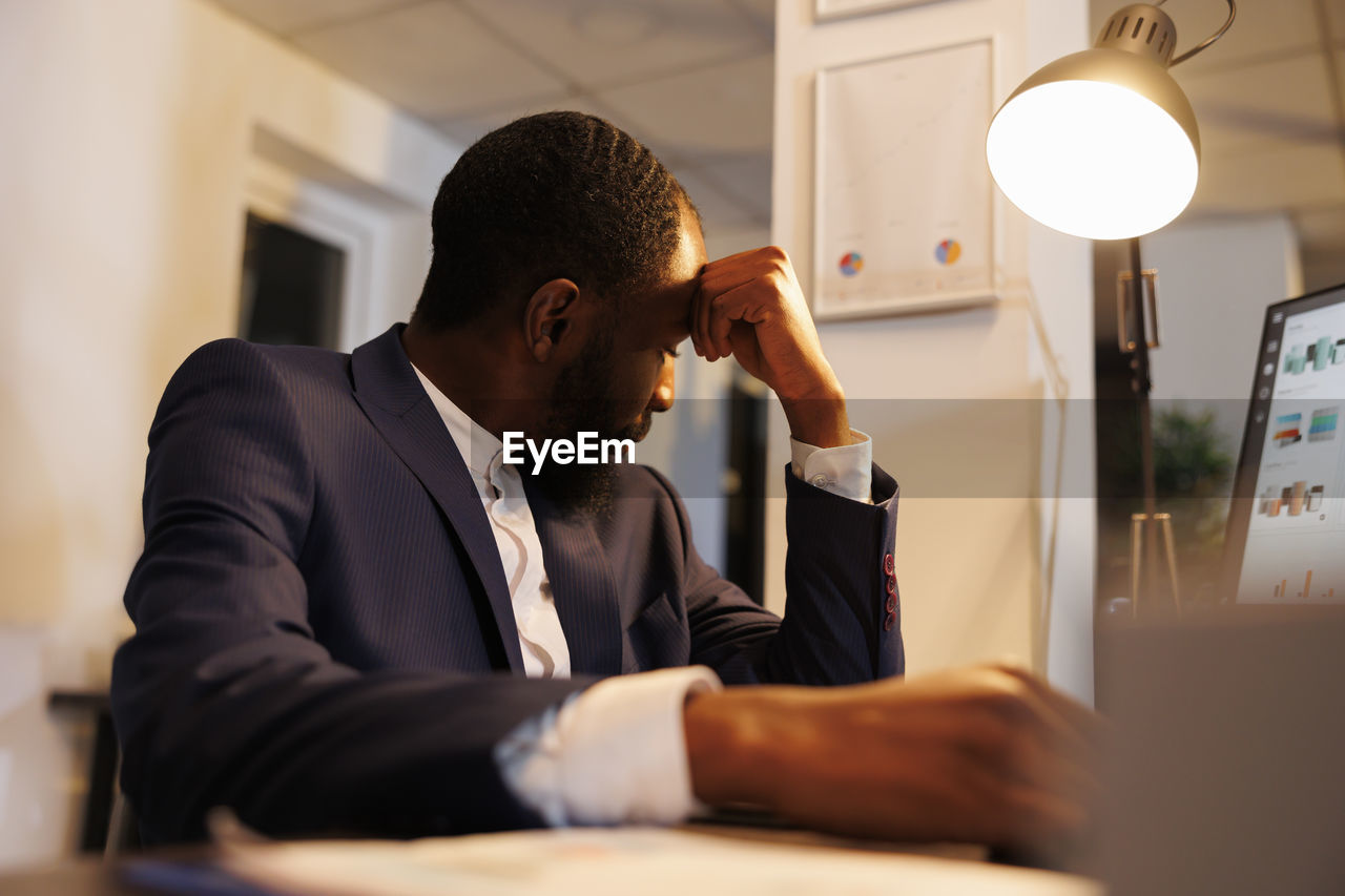 side view of businessman using laptop while sitting in office