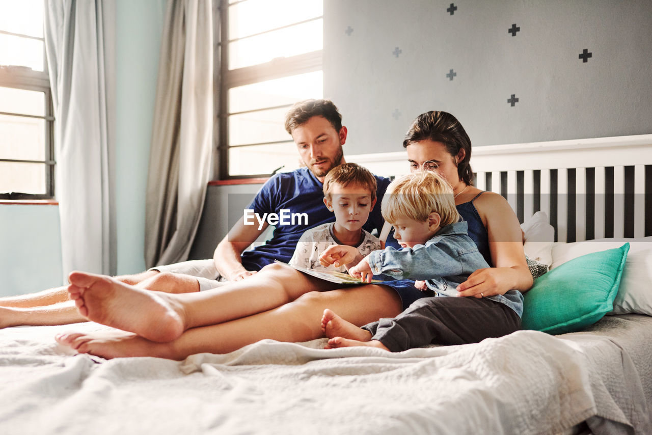 Parents and kids sitting on bed at home