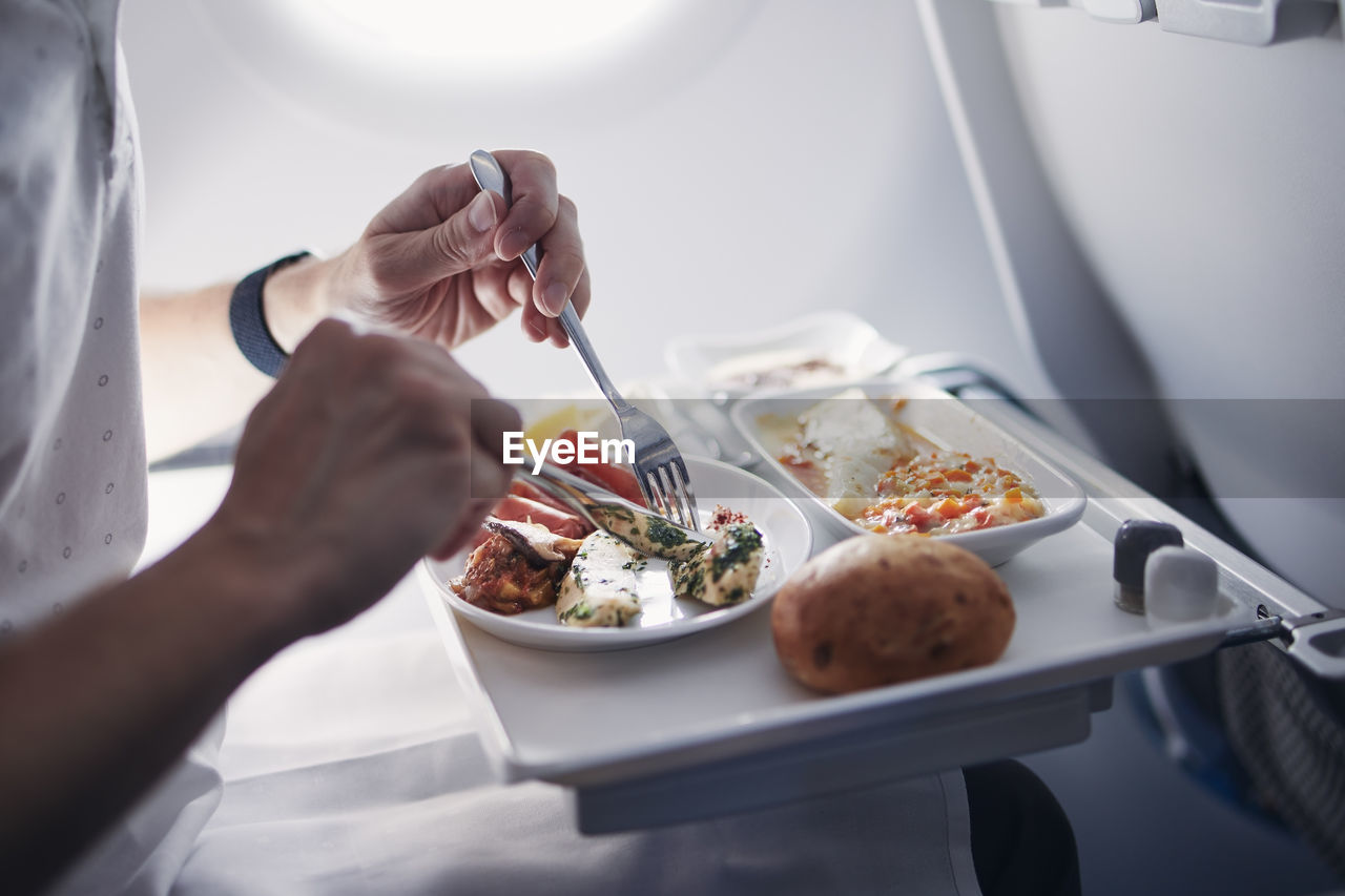 Passenger eating airline meal in airplane. menu in business class on medium haul flight.