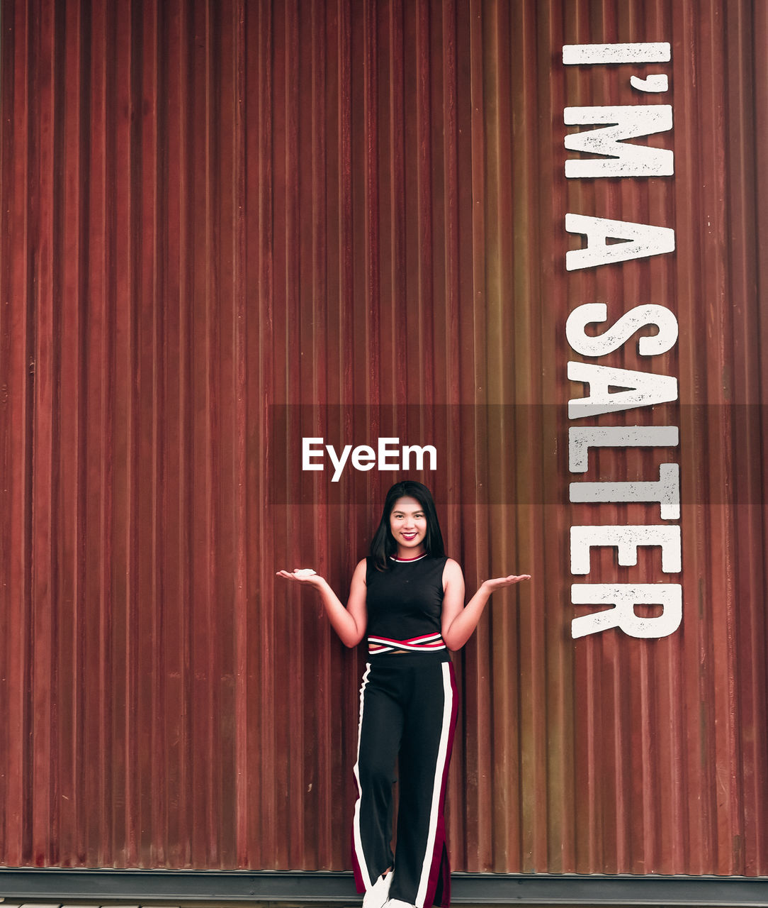 Portrait of smiling young woman standing against cargo container