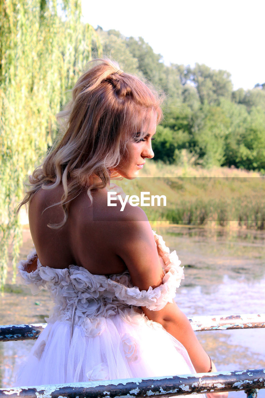 Bride standing on pier over lake