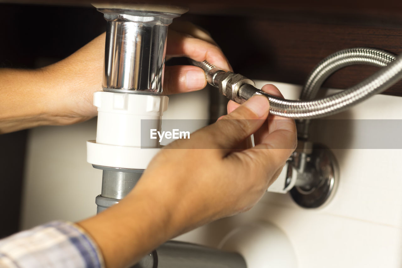 Cropped hands of woman repairing bathroom sink