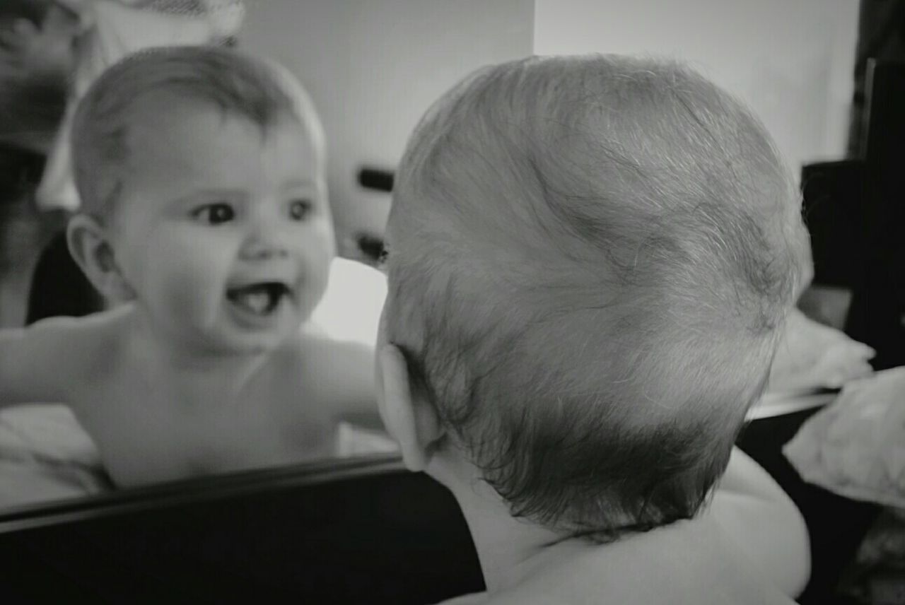 Close-up of baby girl in front of mirror at home