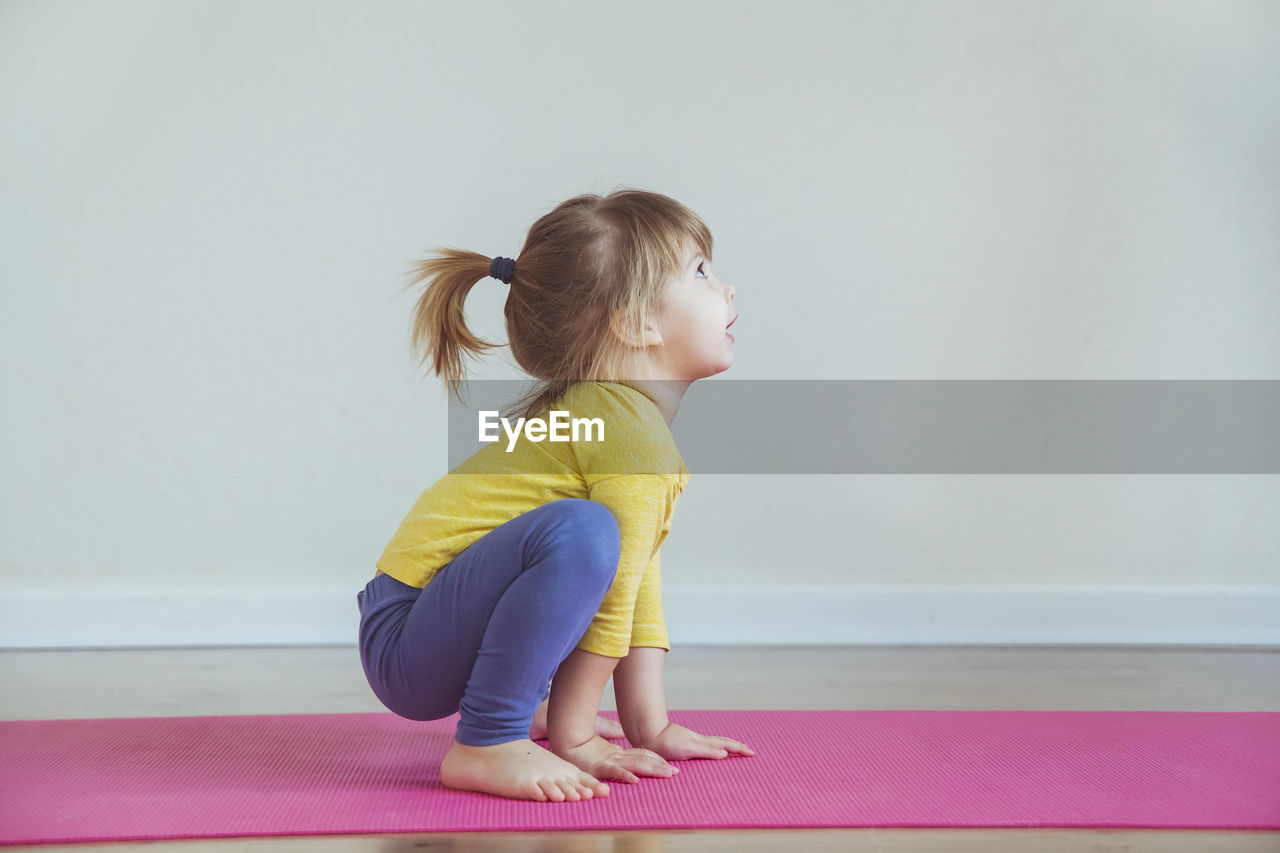 Charming baby doing yoga at home. place for text