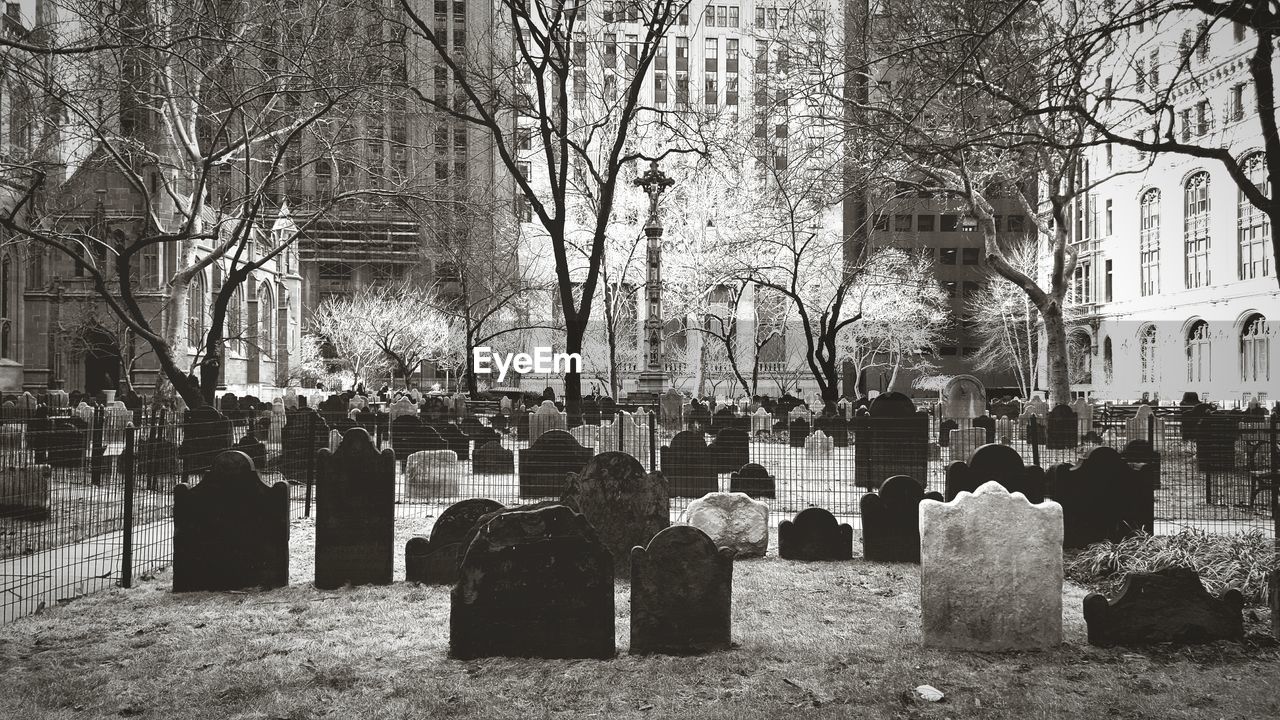 Tombstones at cemetery against buildings in city