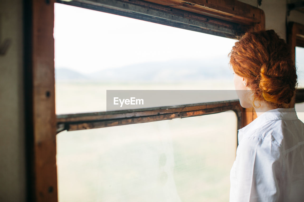 Side view of woman looking through window in train